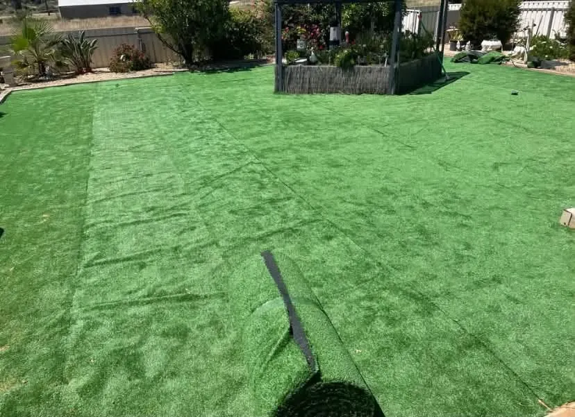 Artificial turf being rolled out across a backyard